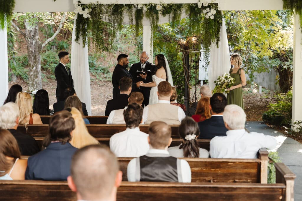Bride and groom saying vows in a woodsy ceremony.