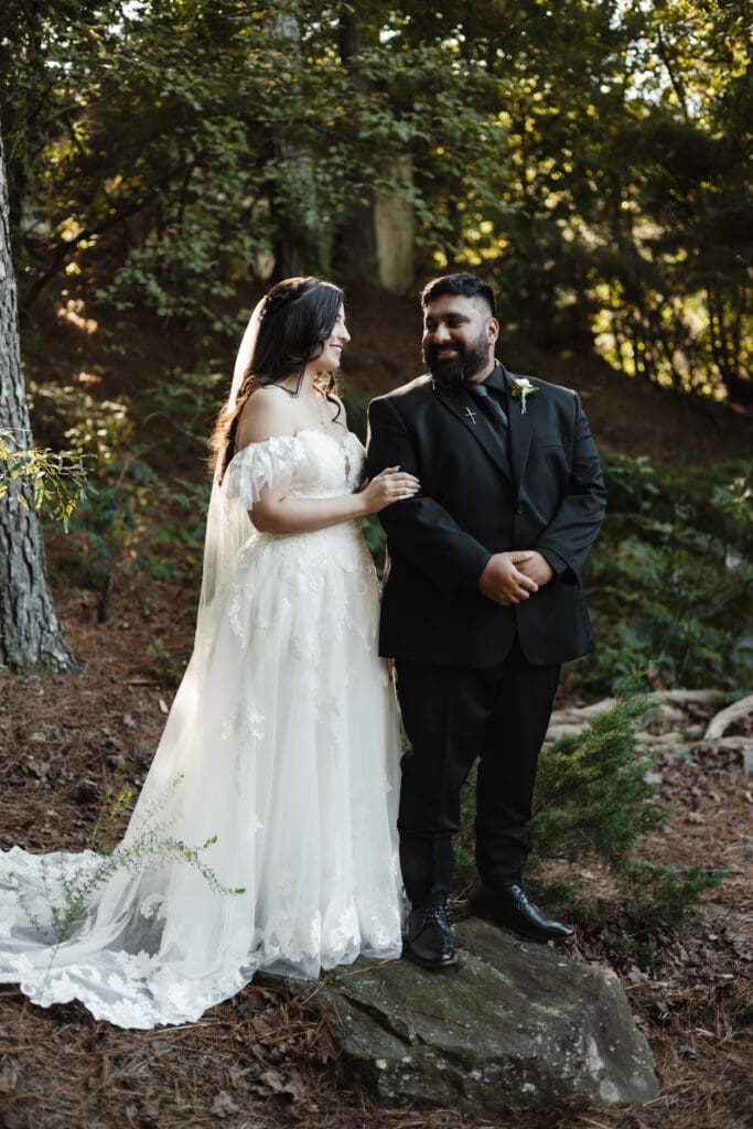 Bride and groom standing together in a Georgia forest during a woodsy fairytale wedding, framed by tall trees and golden sunlight