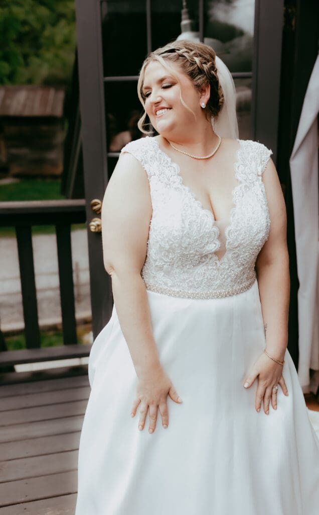 Bride laughing joyfully on her wedding day, wearing a lace gown and veil while standing on a porch, captured in a candid documentary wedding photography style in Georgia.
