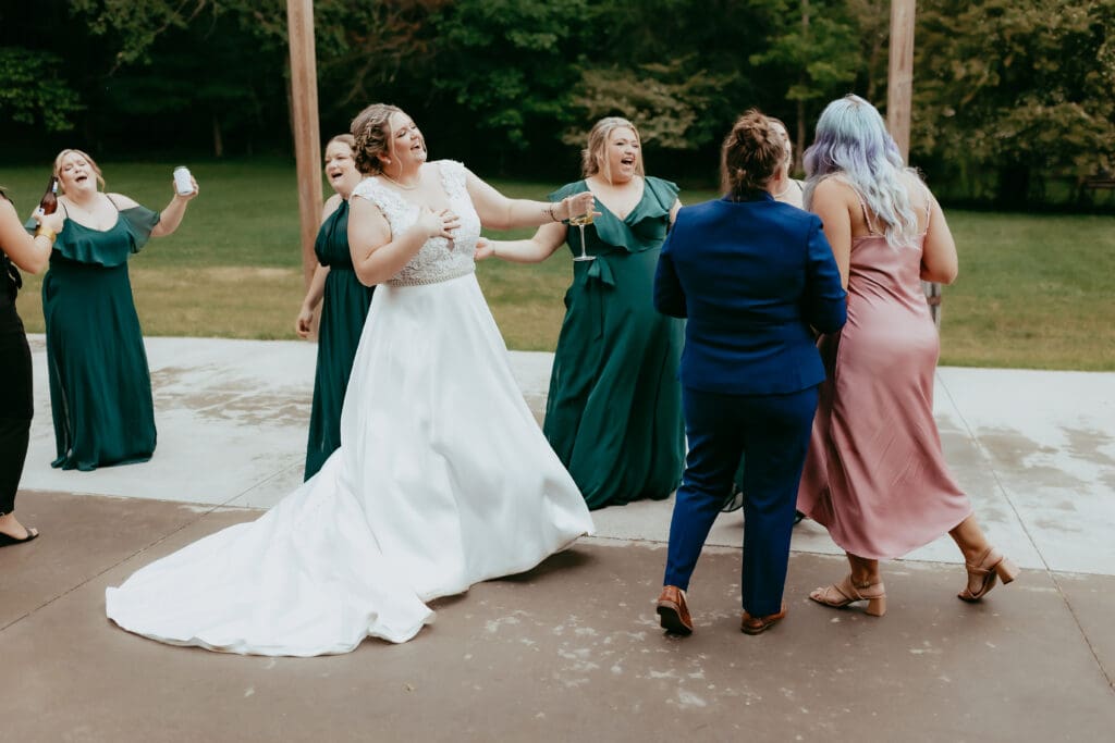 Bride dancing and laughing with friends during an outdoor barn wedding reception in Georgia, captured in an authentic documentary wedding photography style.