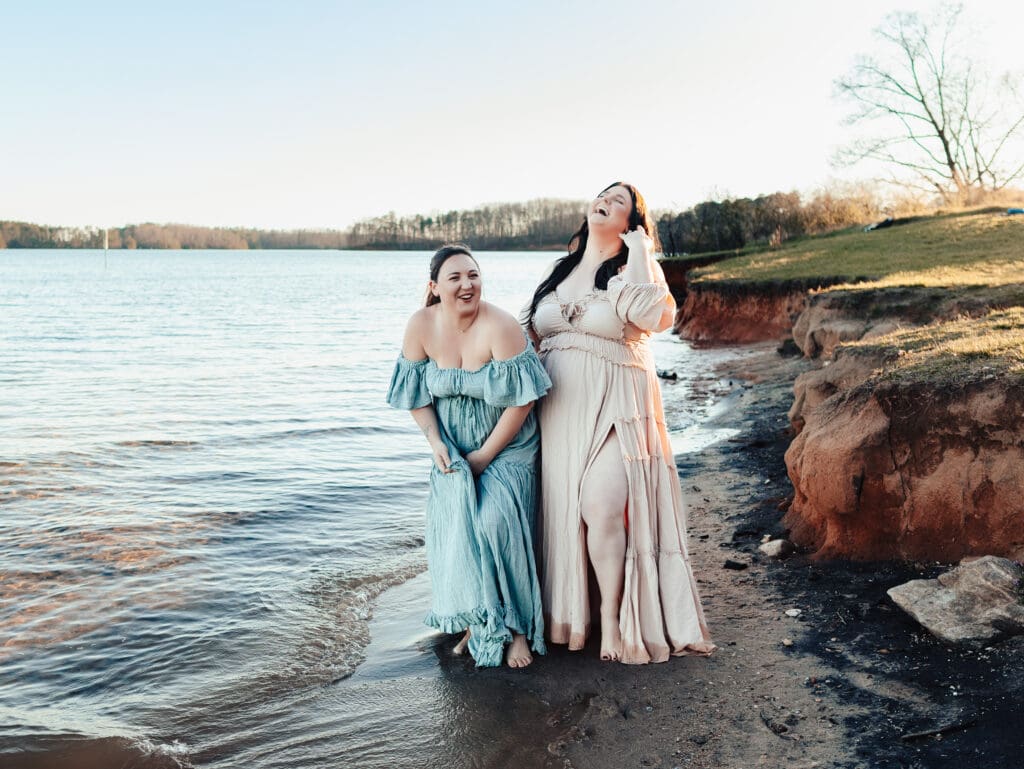 Two women laughing at the lake during a photo session embracing a photography community.