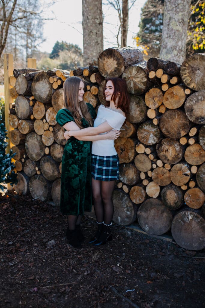 Candid family portrait by a North Georgia family photographer showing sisters embracing and laughing during a winter holiday photo session outdoors.