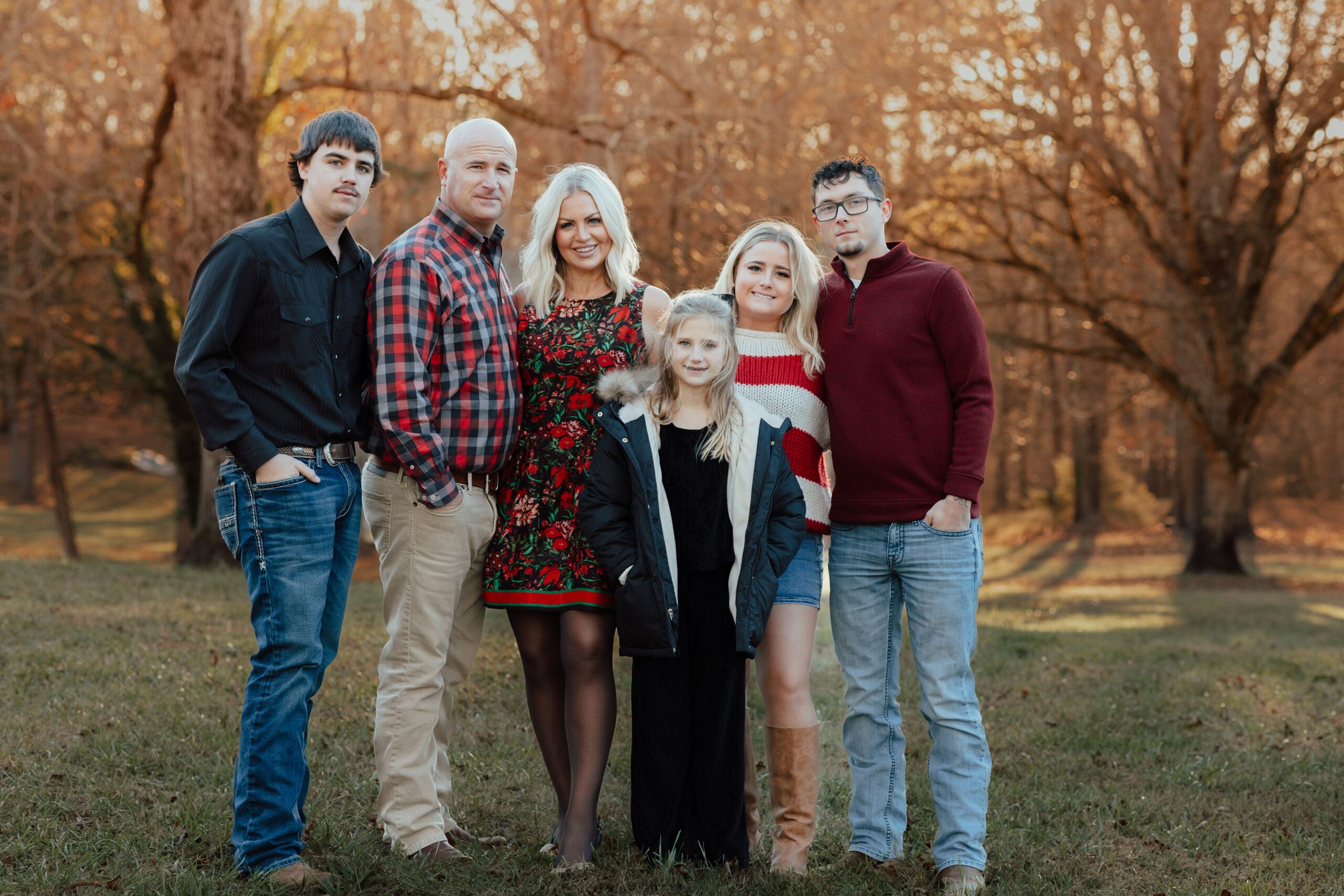 Family portrait captured by a Georgia family photographer during a fall session with parents and grown children standing together in golden autumn light.