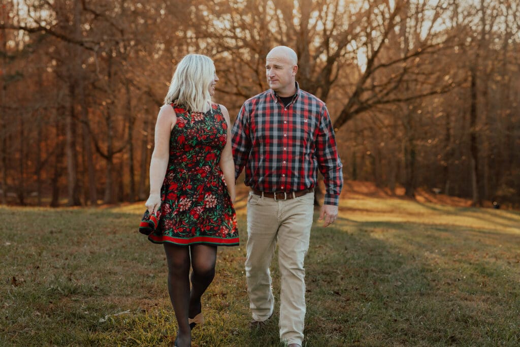 Lifestyle couple walking portrait photographed by a Georgia family photographer during an autumn session in a tree-lined field.
