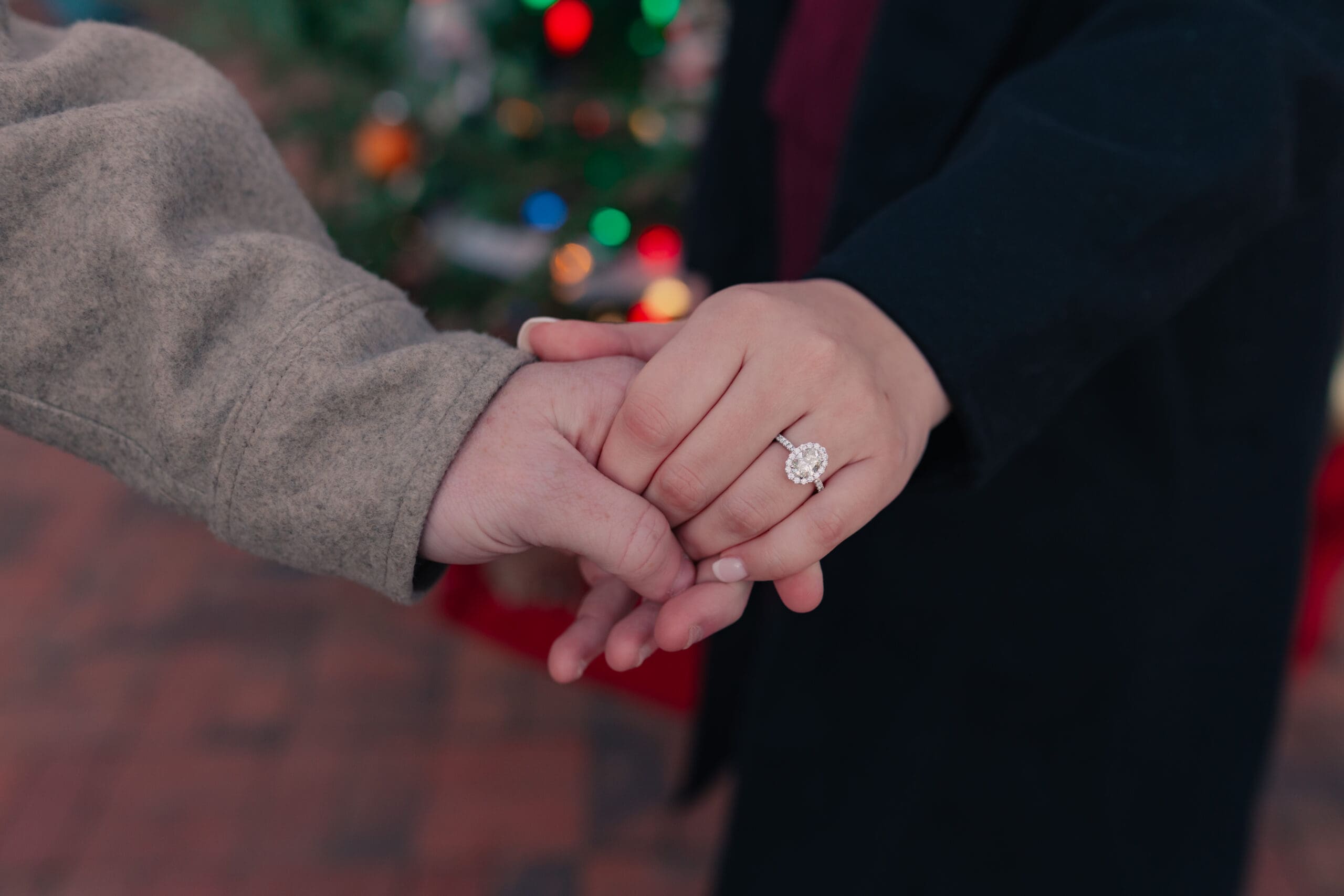 Close-up of engaged hands intertwined, highlighting an engagement ring during a winter engagement session