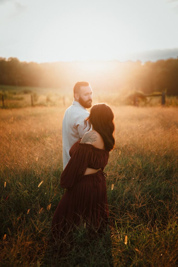 Sentimental maternity photos in Lawrenceville GA showing an expecting couple in a glowing field at sunset, soft light highlighting connection and anticipation.