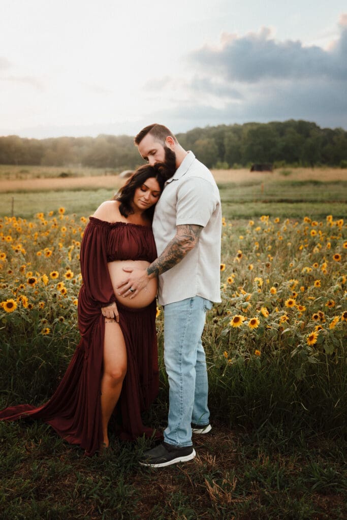 Capturing an intimate outdoor maternity session with expecting parents walking through a sunflower field at golden hour, warm light and soft movement.