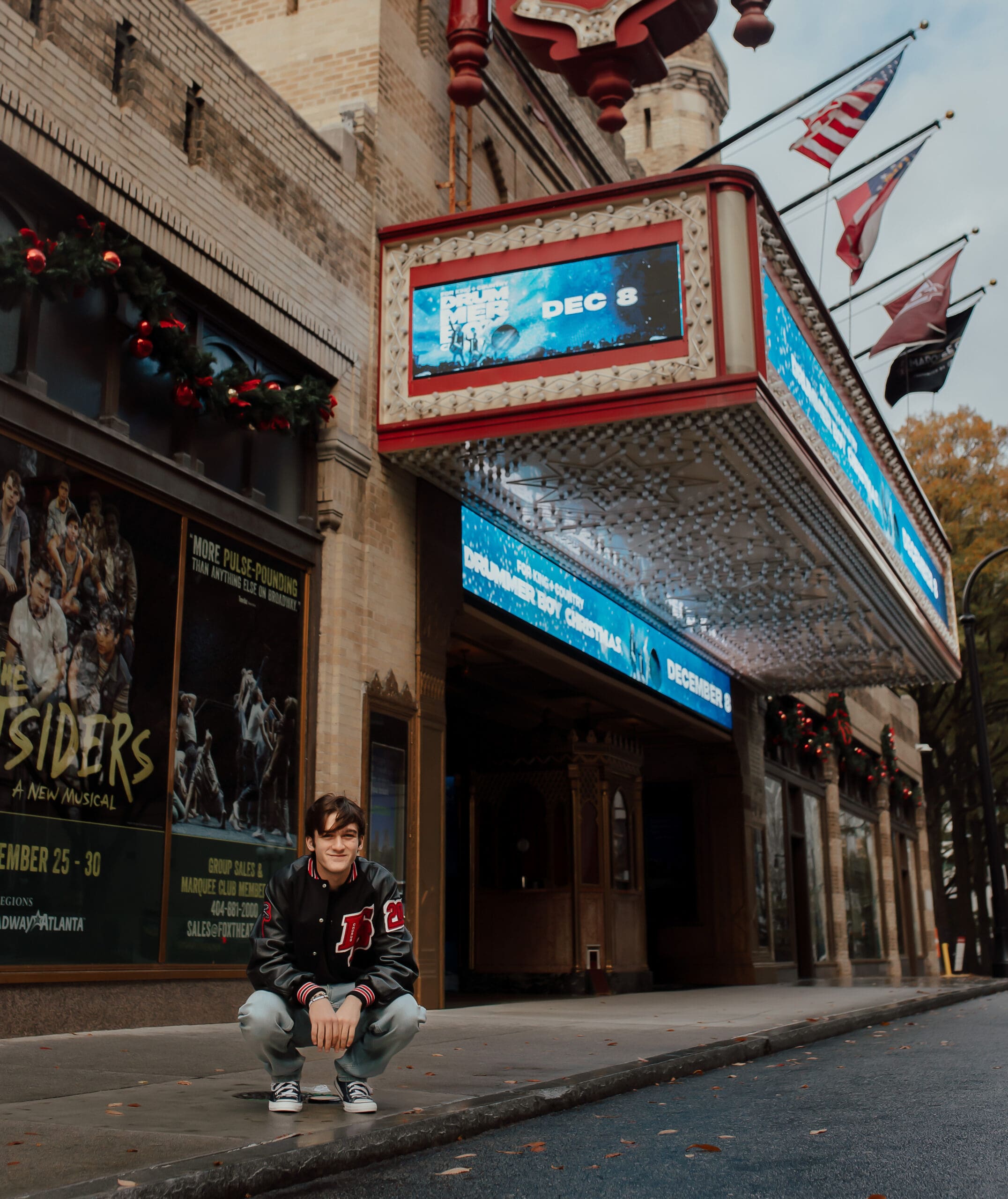 Senior boy posing outside the Fox Theatre in Atlanta during a cinematic senior session with marquee lights overhead