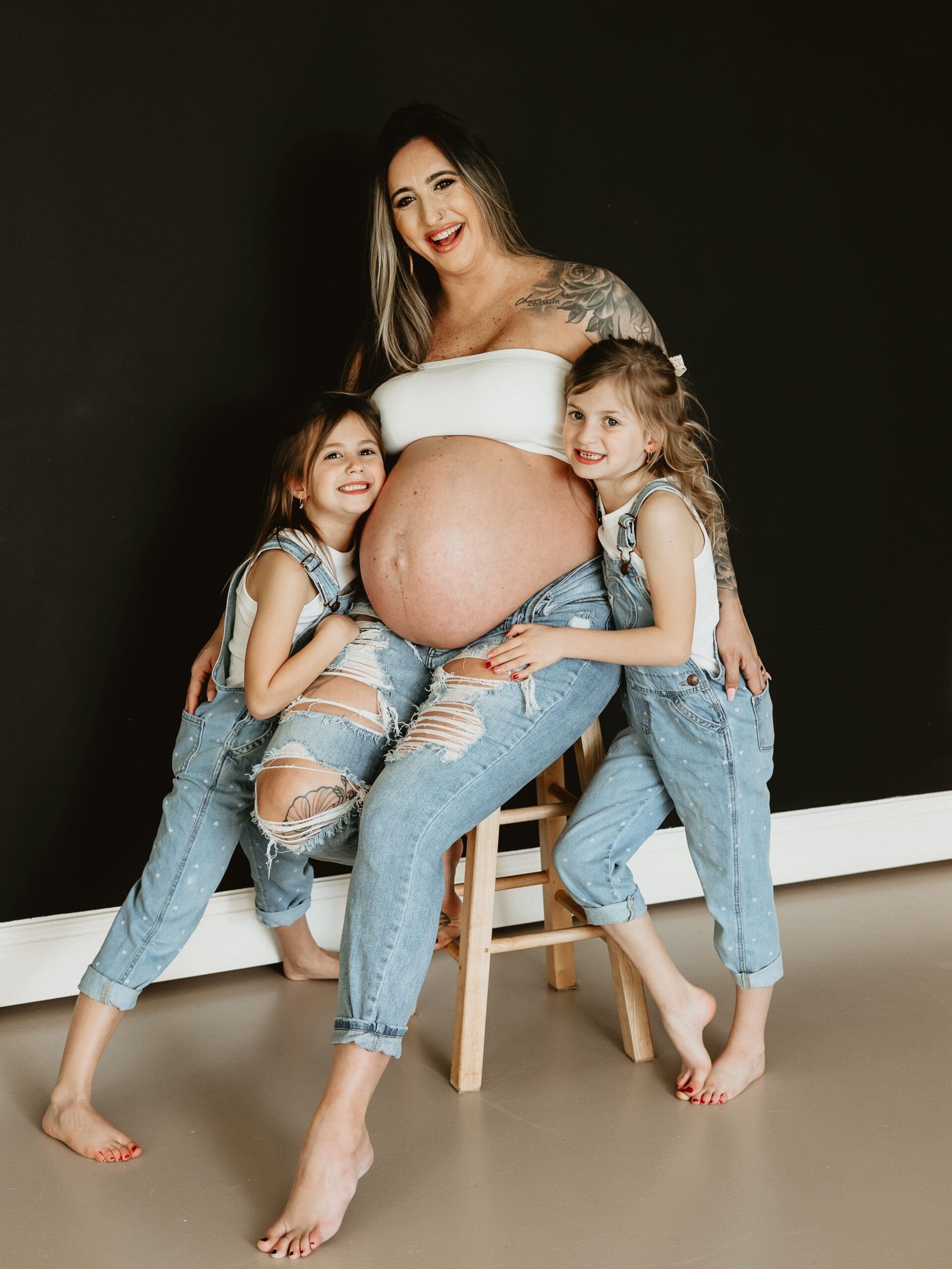 Motherhood maternity session in Cumming Georgia with two daughters hugging their pregnant mom’s belly during a Wildhaven Studio maternity photography session.