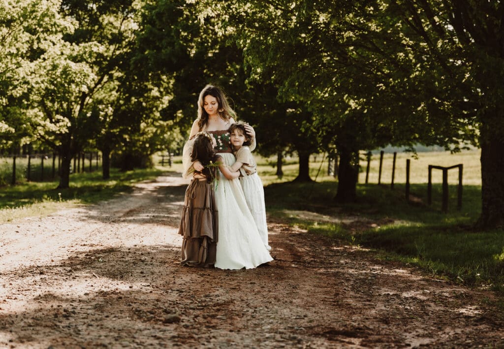 Mother hugging her two children on a country road during a motherhood session at Powell Barn during golden hour.