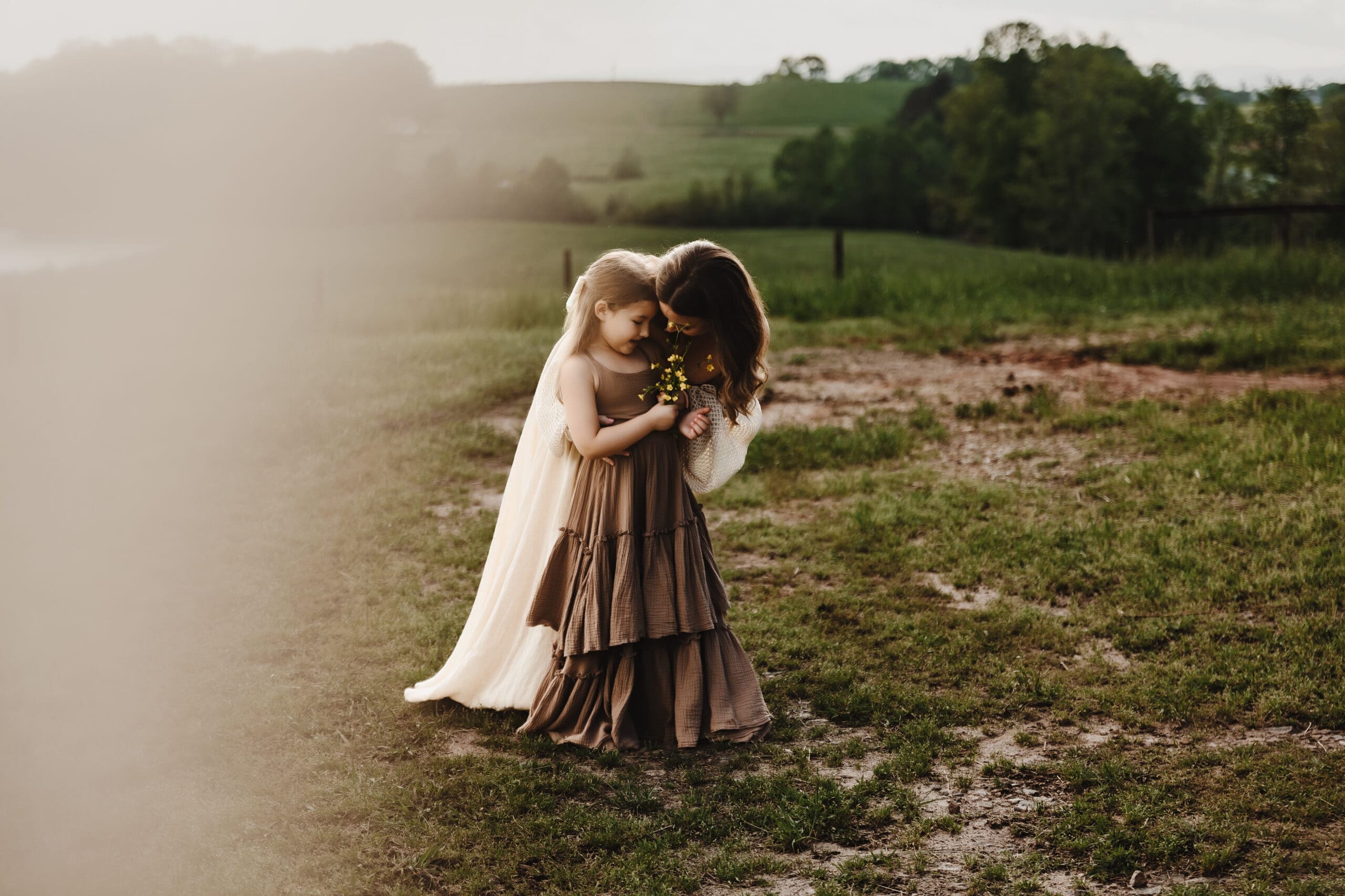 Mother holding her daughter in a field during golden hour motherhood photography at Powell Barn.