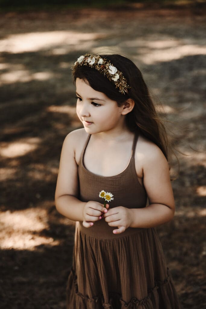 Little girl holding a daisy during a Cleveland Georgia motherhood photography session at Powell Barn in the North Georgia mountains.