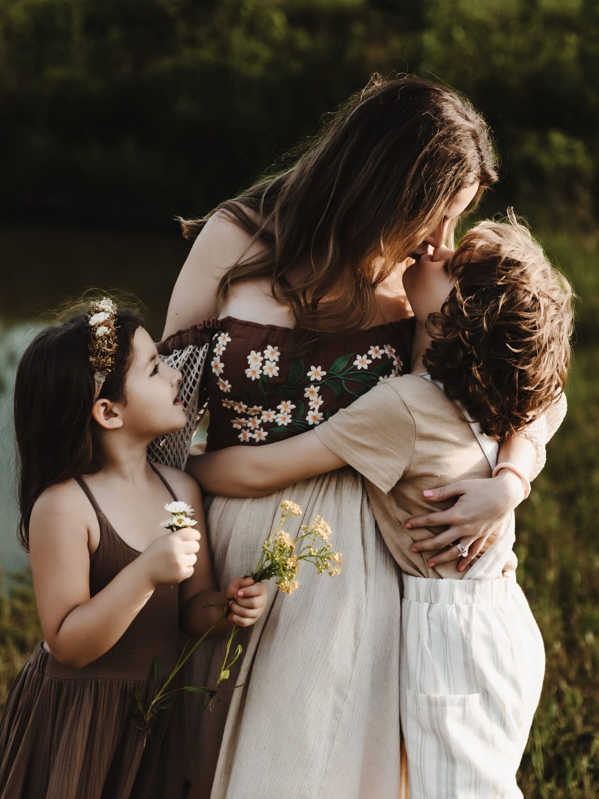 Son kissing his mother while holding flowers during a Cleveland Georgia motherhood photography session at Powell Barn in Cleveland GA.