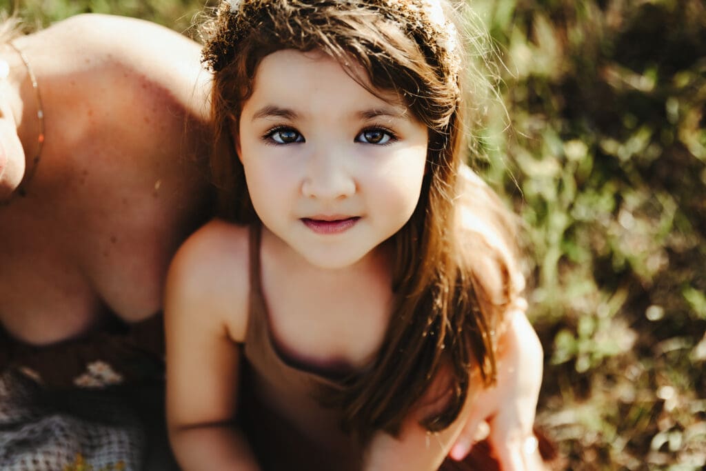 Close up portrait of little girl during a motherhood photography session in golden hour light.